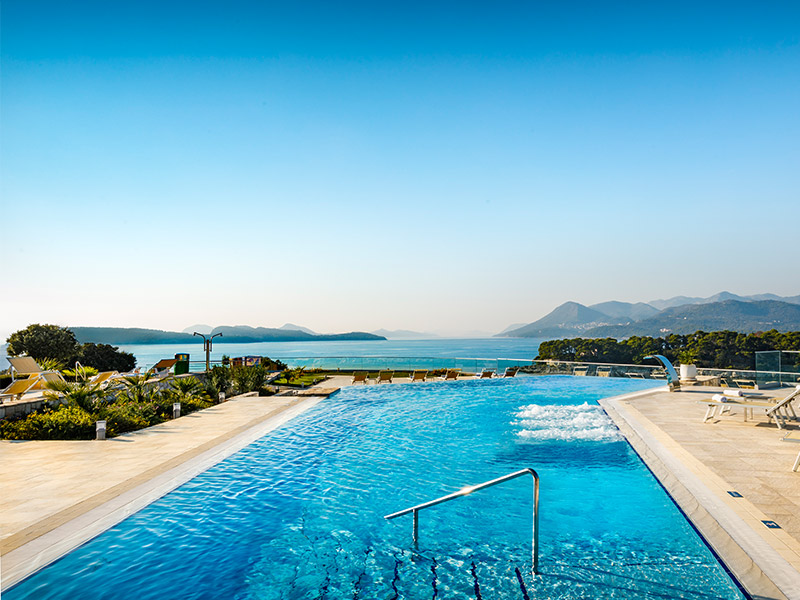 Zunanji bazen v hotelu Argosy v Dubrovniku s čudovitim razgledom na morje in veličastne gore v ozadju.