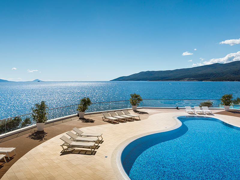 Heated and partially covered Children's pool with sun loungers and umbrellas at the Girandella Valamar Collection Resort