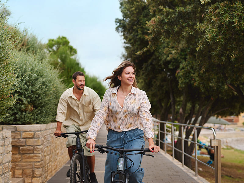 Coppia in bicicletta lungo il sentiero sul mare in un campeggio Valamar.