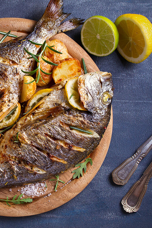 Traditional grilled fish with potatoes and lemon.