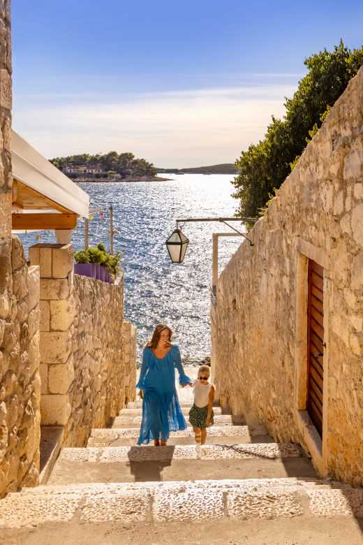 Deklica se nasmehne, medtem ko se rakovica Maro v ozadju igra z otroki.