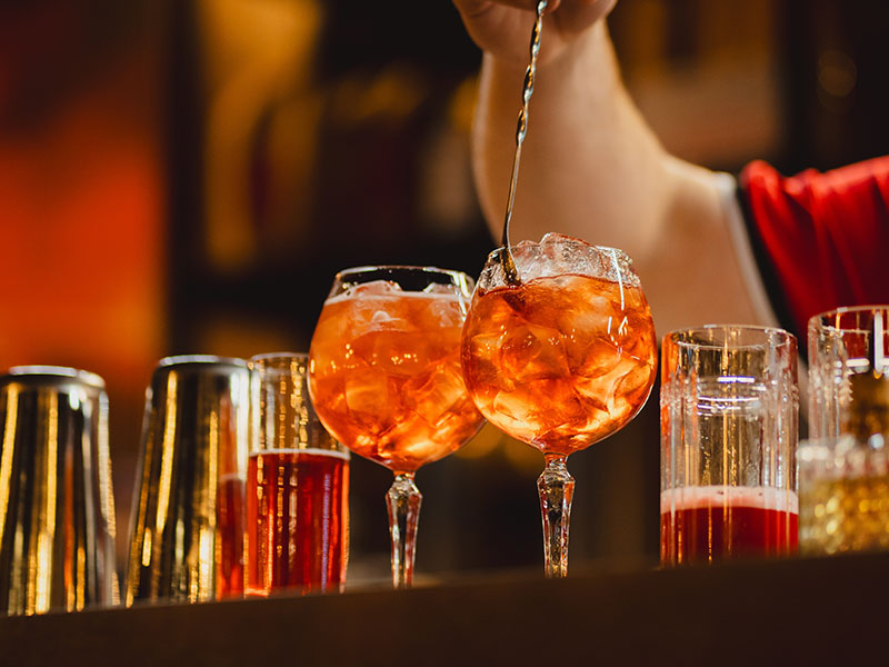 Barman představuje koktejl v tlumeně osvětleném baru