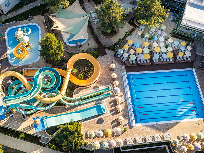 Vue aérienne des piscines extérieures et des toboggans aquatiques colorés au Valamar Diamant Hotel.