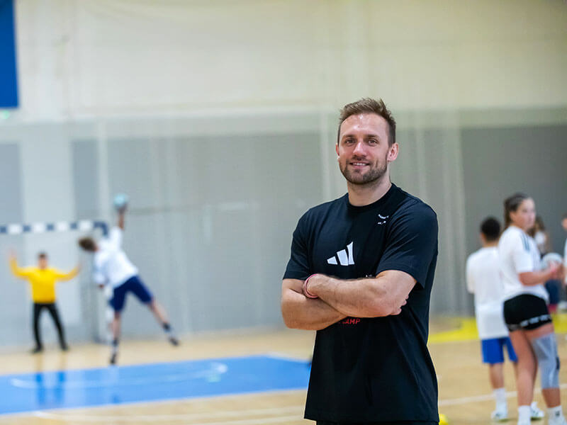 Coach standing in the sports hall at Valamar Diamant Hotel as young players train during handball camp