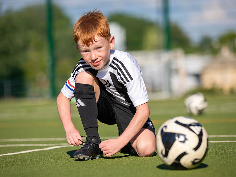 Boy tying his football boot on the pitch at the Juventus training camp in Funtana near Poreč