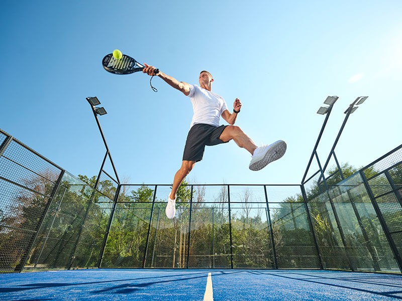 Woman playing padel on an outdoor court at Racket Club.