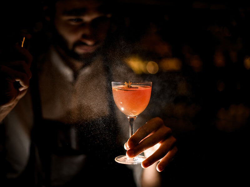 Bartender presenting a cocktail in a dimly lit bar
