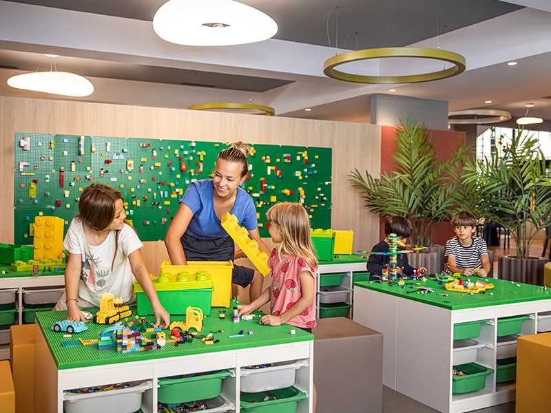 Children engaged in paper crafts at a table, supervised by Maro babysitters