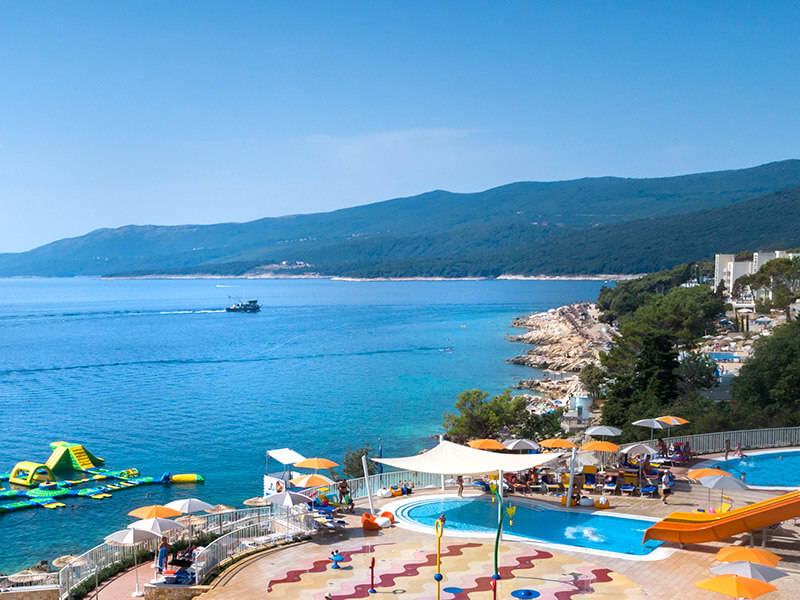 Grijani i djelomično natkriveni dječji bazen s ležaljkama i suncobranima u Girandella Valamar Collection Resort