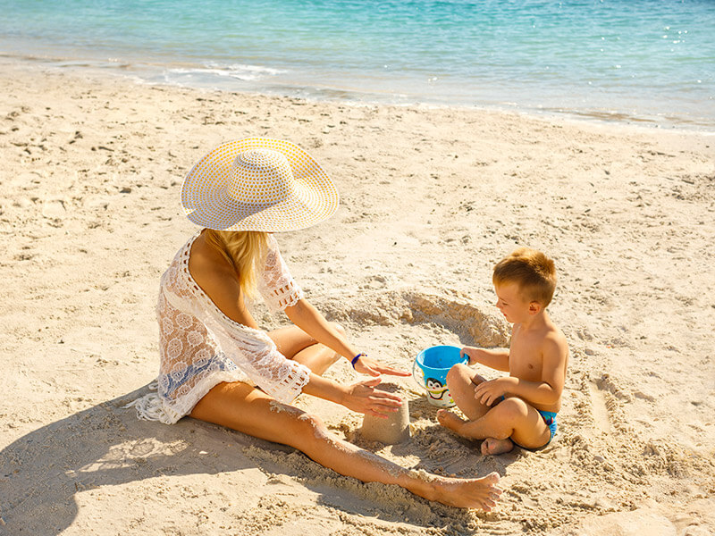 Kobieta i jej syn bawią się w piasku na piaszczystej rodzinnej plaży Val Sundance