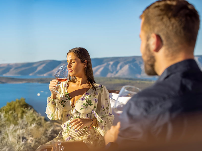 Ženska srka vino med obiskom vinograda na Hvaru s pogledom na morje