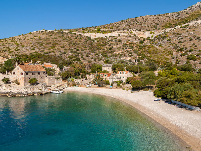 Povijesna kamena kuća na plaži Dubovica s mirnim valovima Jadrana