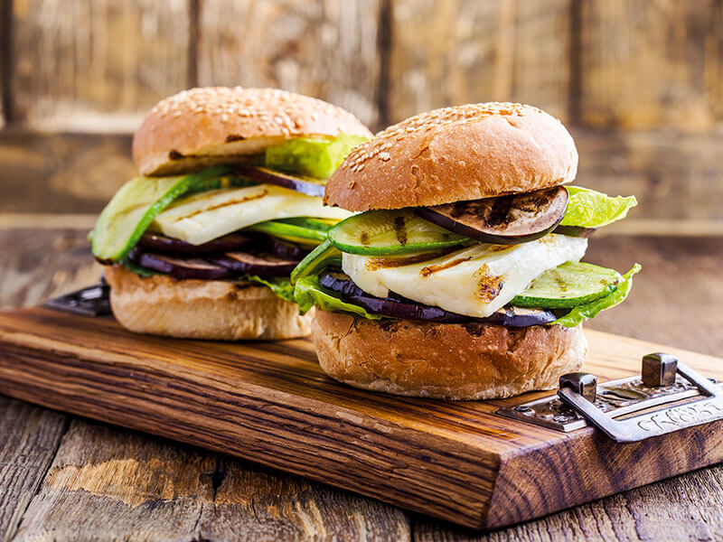 Gurmanski burger s svežimi dodatki na rustikalni leseni deski