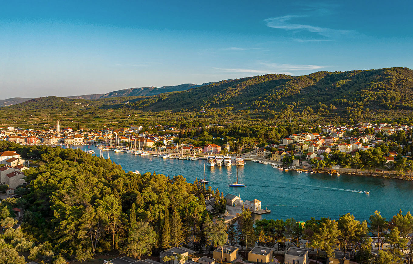 Boote vor Anker im Hafen von Hvar mit traditionellen Häusern und bewaldeten Hügeln