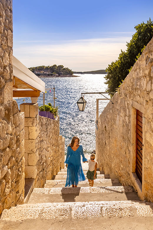 Frau und Kind erkunden eine historische Steingasse in der Stadt Hvar