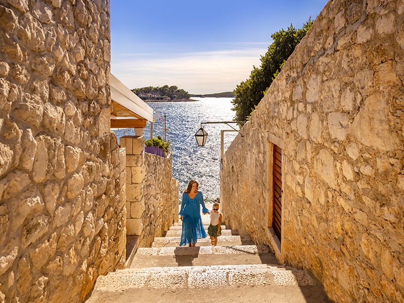 Žena a dieťa objavujú historickú kamennú uličku v meste Hvar