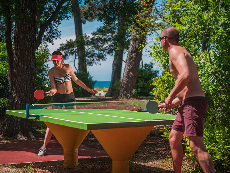 Par igra stolni tenis u hladu šume blizu mora.