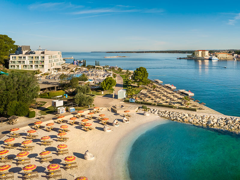 Ležaljke na stjenovitom brežuljku s pogledom na šljunčanu plažu Val Sunrise Relax