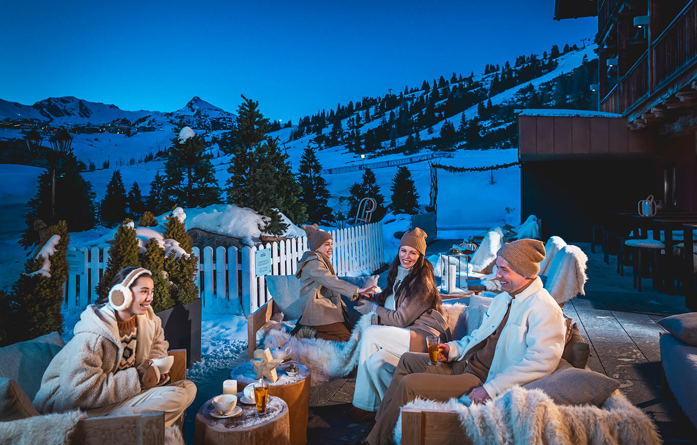 Eine Gruppe von Freunden entspannt sich auf der Après-Ski-Lounge-Terrasse mit Bergblick im Kesselspitze Hotel & Chalet
