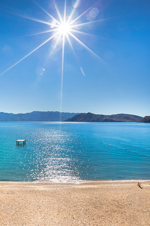 Plaža na otoku Krku s kristalno čistim morem i podnevnim suncem