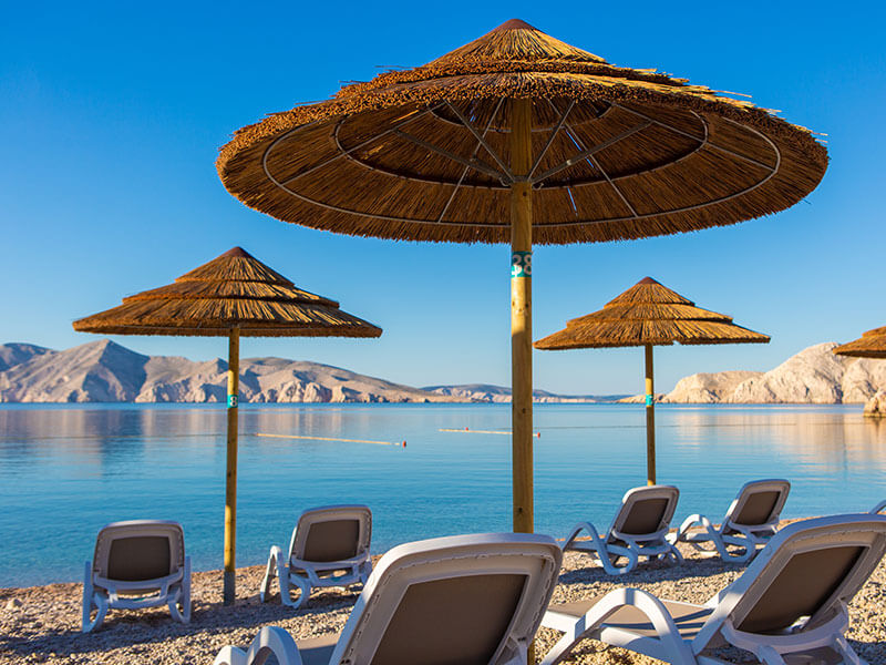 Nudistička plaža Bunculuka sa slamnatim suncobranima i pogledom na more