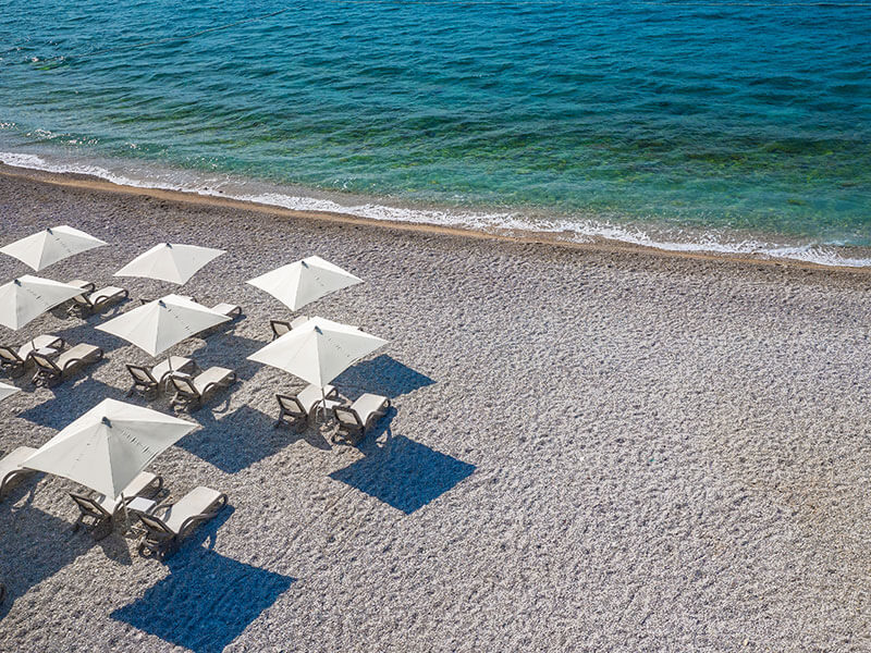 Suncobrani i ležaljke u nizu na plaži Oprna