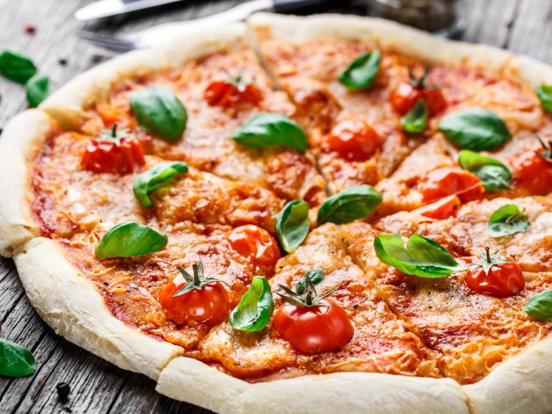 Pizza cotta nel forno a legna con basilico, mozzarella e pomodoro