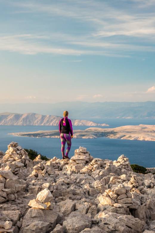 Hiker enjoying panoramic views of islands and coastline on an excursion in Kvarner, Croatia.