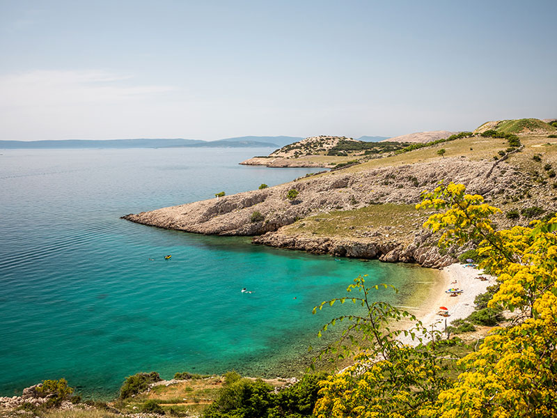 Secluded pebble beach with turquoise sea and rocky coastline in Kvarner