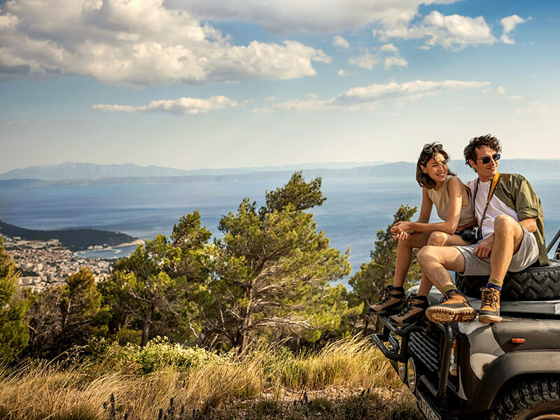 Turisti oddychujú pri džípe s panoramatickým výhľadom na Jadran