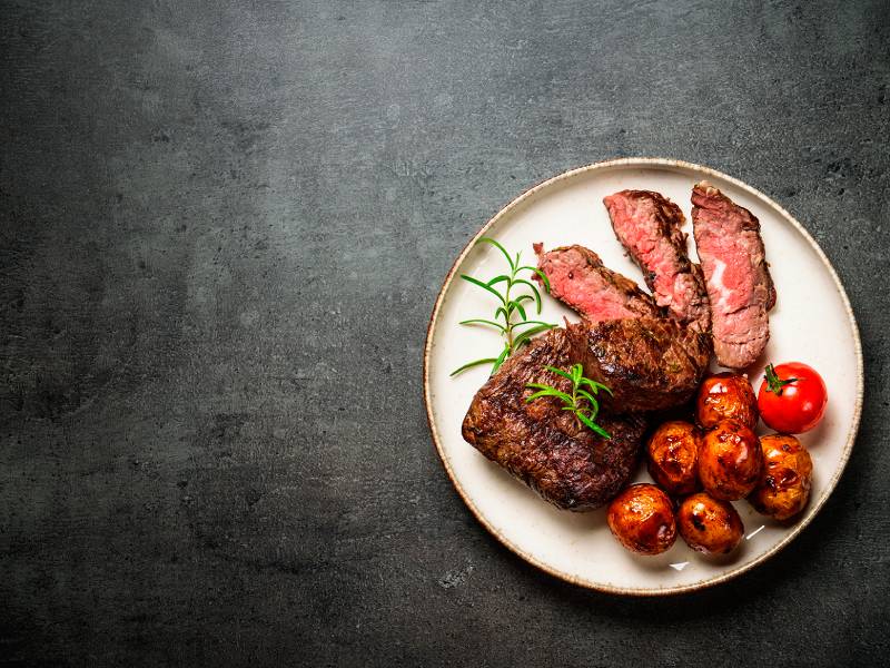 Piatto di carne raffinato servito su piatto in ceramica rustica