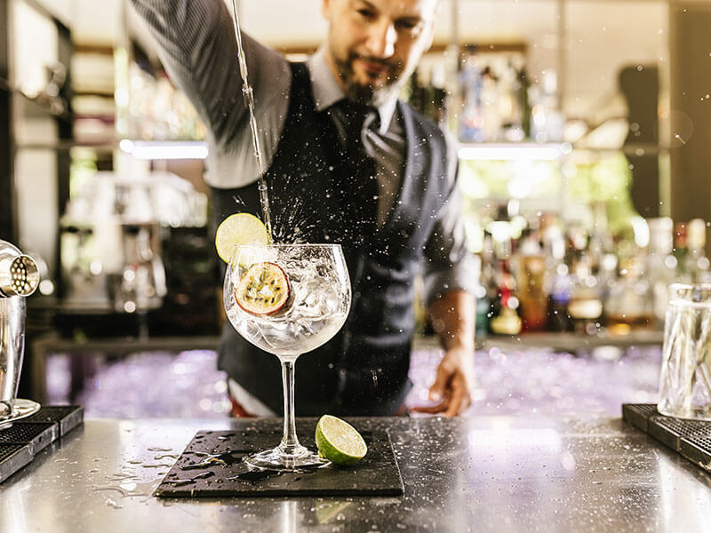 Barista serve un cocktail al gin con erbe aromatiche