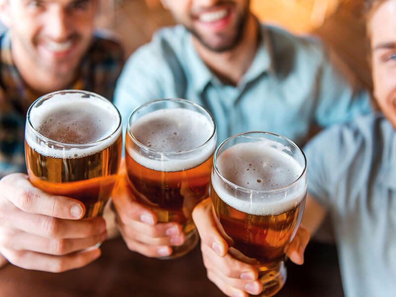Gruppo di amici brinda con birre in un pub locale