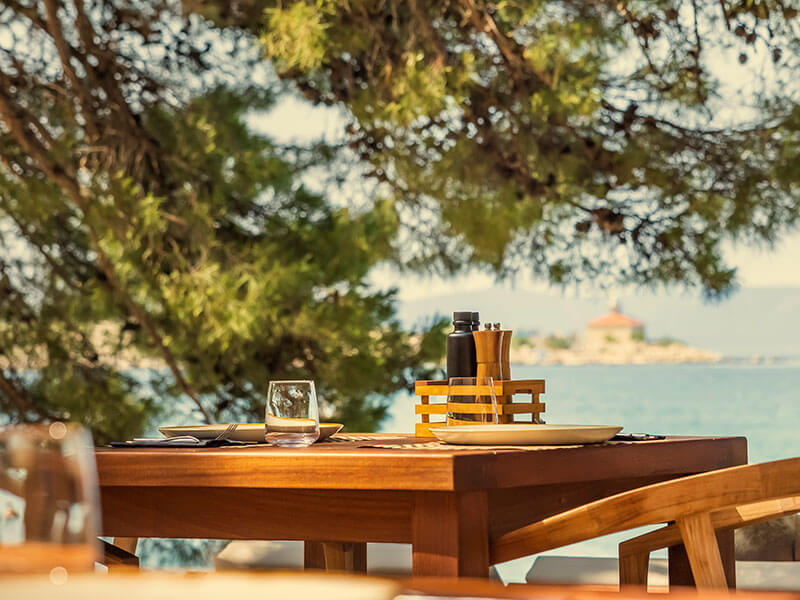 Tavolo in un ristorante sulla spiaggia a Makarska, all’ombra dei pini