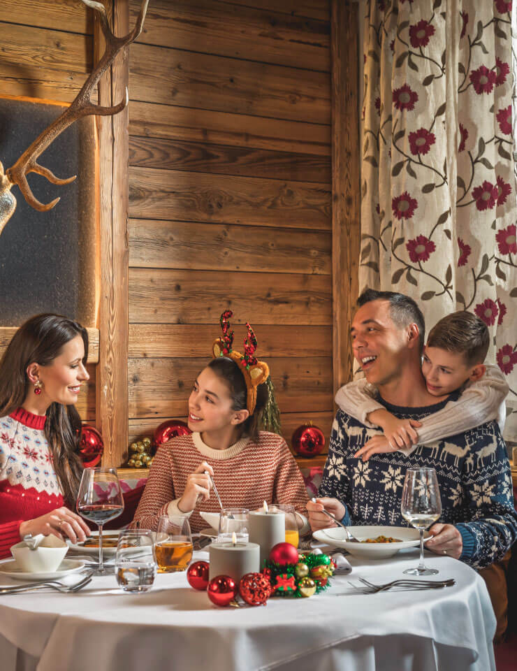 Family enjoying a festive Christmas dinner in a cosy alpine setting.