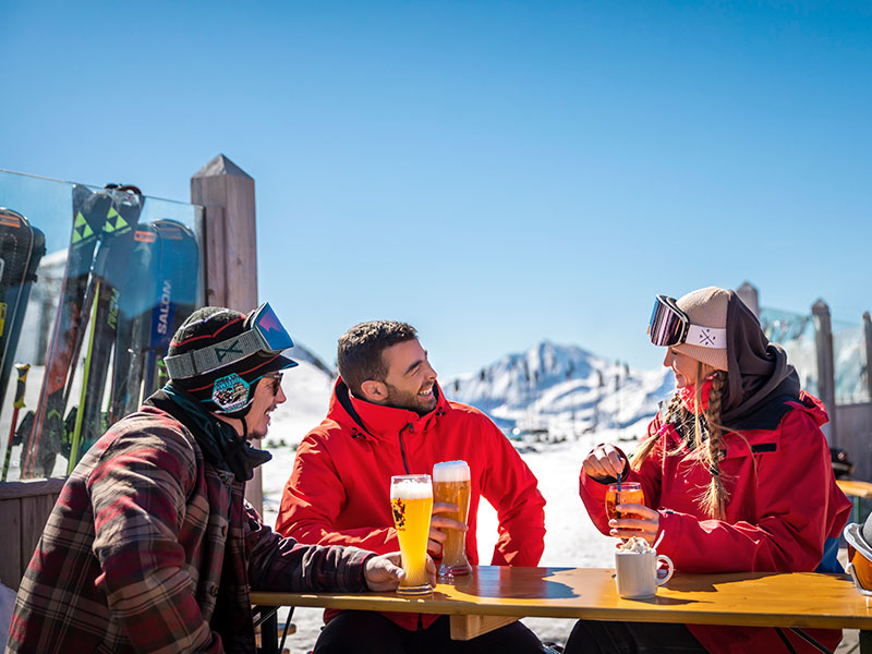 Drei Freunde sitzen in einer Après-Ski-Bar am Gipfel von Österreichs schneereichstem Skigebiet