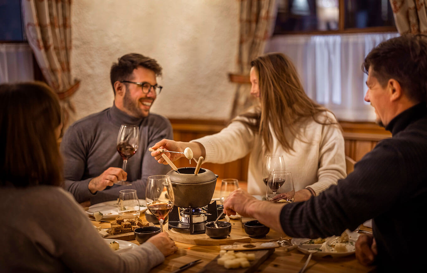 Skupina priateľov si pochutnáva na syrovom fondue