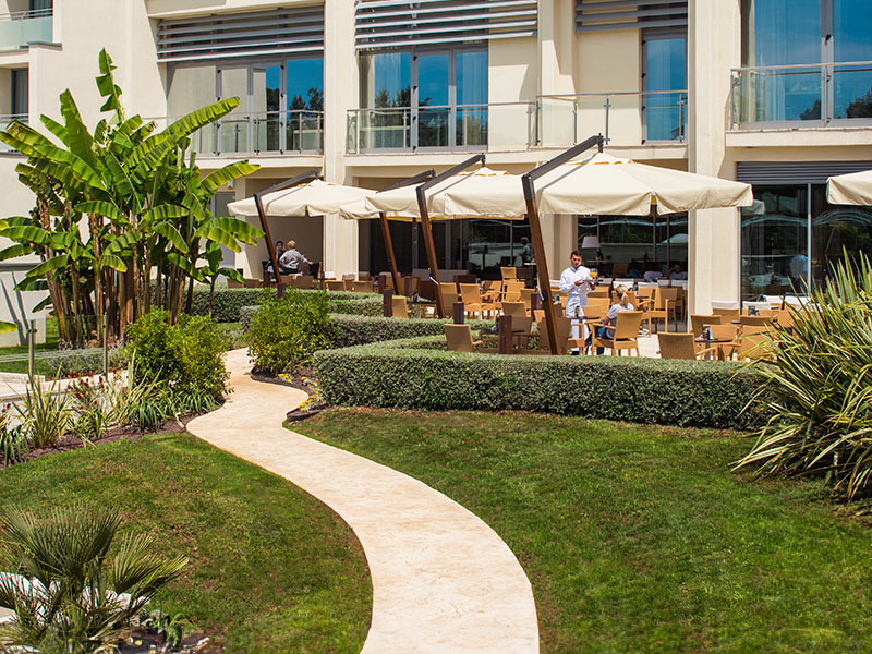 Coppia che beve cocktail sulla terrazza soleggiata del Miramare Lobby Bar con vista sul mare.