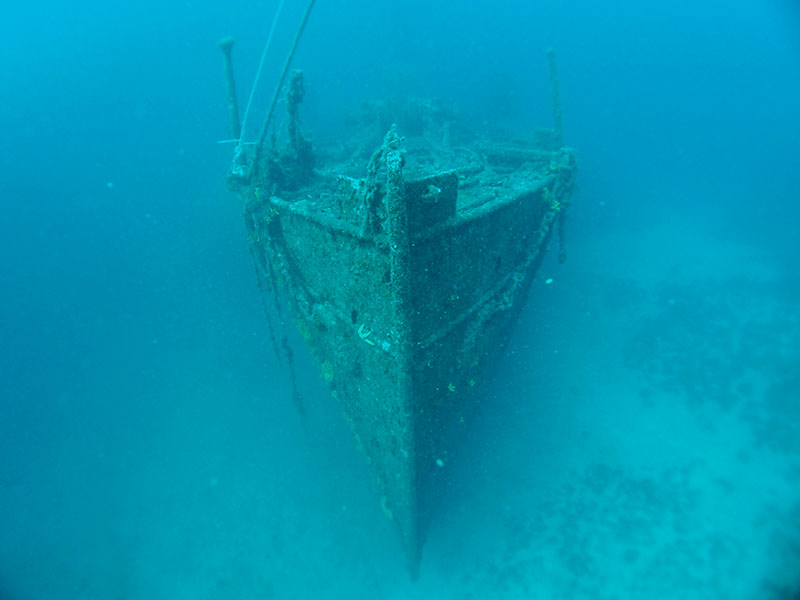 Sunken shipwreck resting on the seafloor, covered in marine growth
