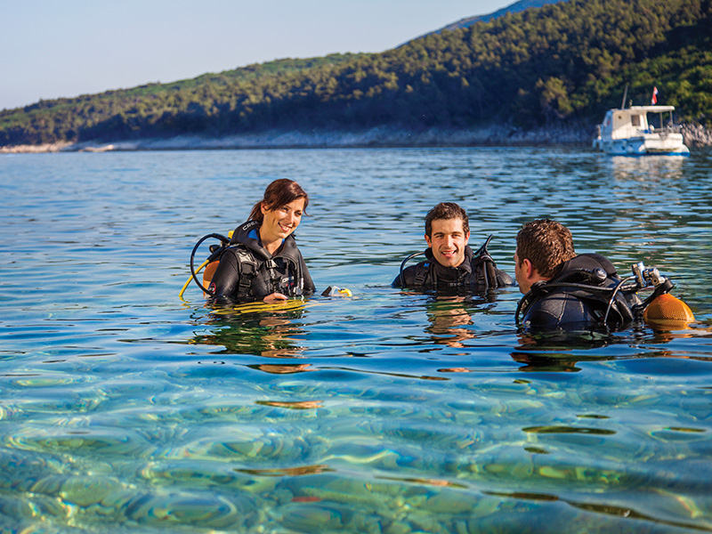 Group of divers preparing to dive at Lim Shoals in clear coastal waters