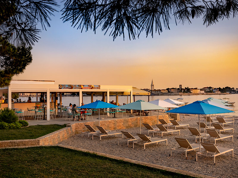 Beach bar and sun loungers at Parentino Beach with views of Poreč old town