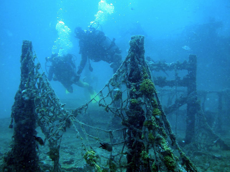 Submerged shipwreck entangled in fishing nets on the seafloor