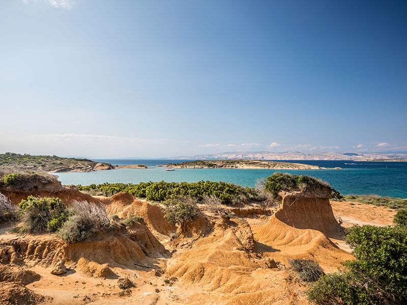 Abgelegener Naturstrand mit felsigem Gelände und niedriger Vegetation am Ciganka Beach