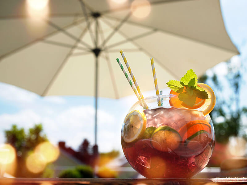 Pisani poletni koktajl z limeto in senčnikom na mizi ob plažnem baru