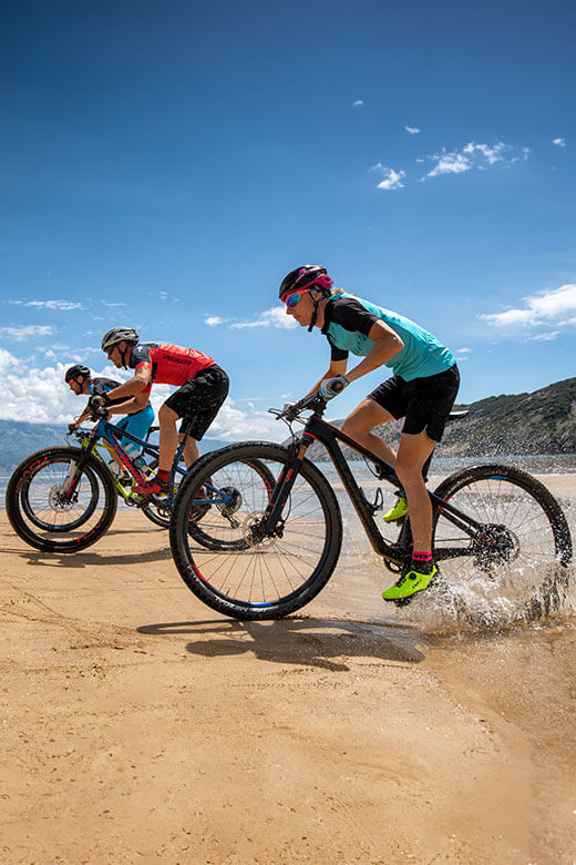 Cyclistes en VTT longeant la plage de sable de l’île de Rab