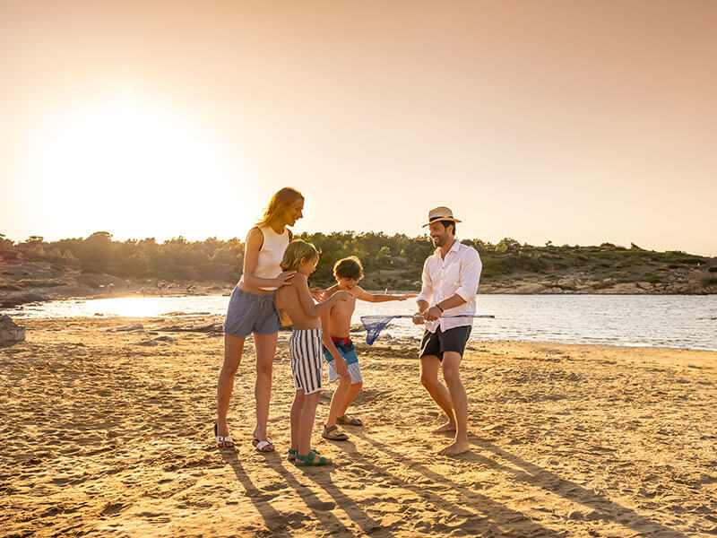 Famille jouant sur une plage de sable au coucher du soleil pendant des vacances sur l’île de Rab