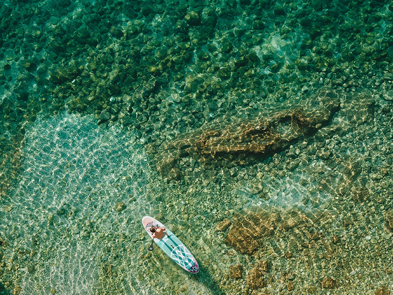 Schnorchler schwimmt über felsigem Meeresboden im klaren Wasser an einem Strand auf Rab