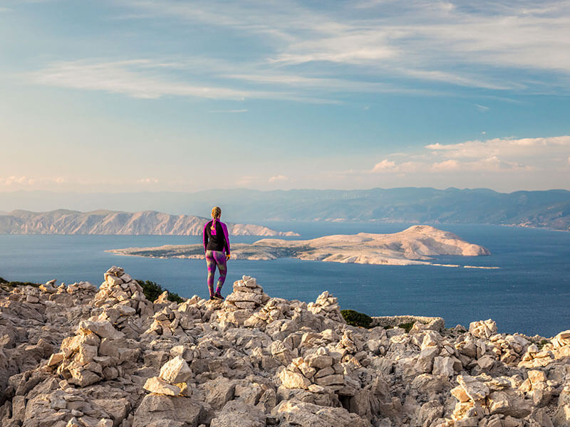 Hiker standing on Kamenjak Peak with island views