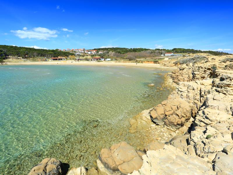 Weite flache Bucht mit ruhigem, klarem Wasser und Sandufer am Livačina Beach