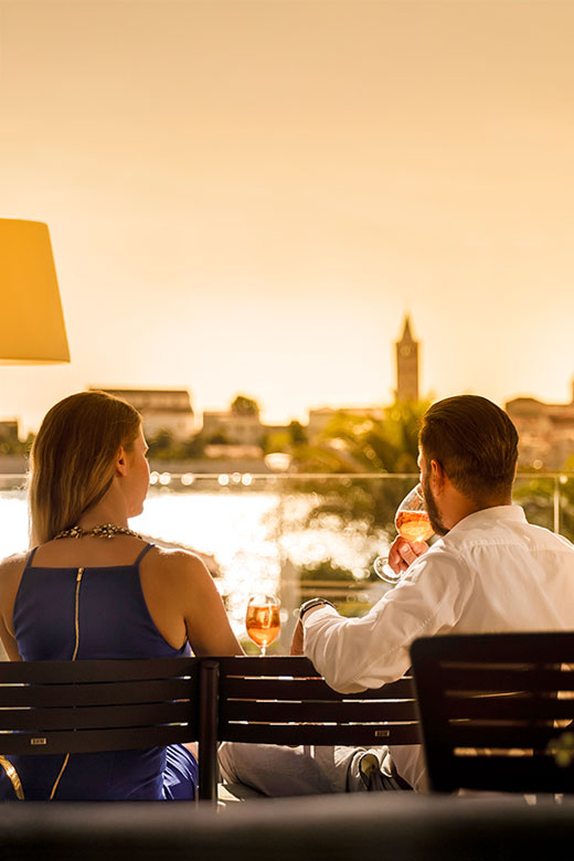 Détente avec un verre de vin face à la vieille ville de Rab au coucher du soleil